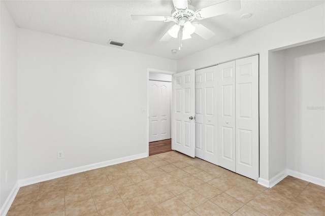 unfurnished bedroom with a textured ceiling, ceiling fan, light tile patterned floors, and a closet