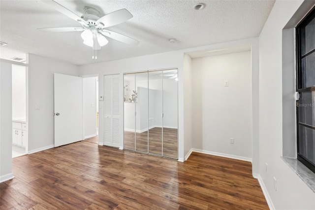 unfurnished bedroom with ceiling fan, a textured ceiling, and dark hardwood / wood-style flooring