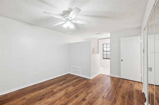 empty room with ceiling fan, dark wood-type flooring, and a textured ceiling