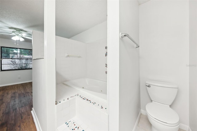 bathroom featuring wood-type flooring, a textured ceiling, toilet, and a bath