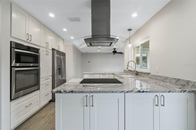 kitchen featuring sink, kitchen peninsula, island range hood, and white cabinetry