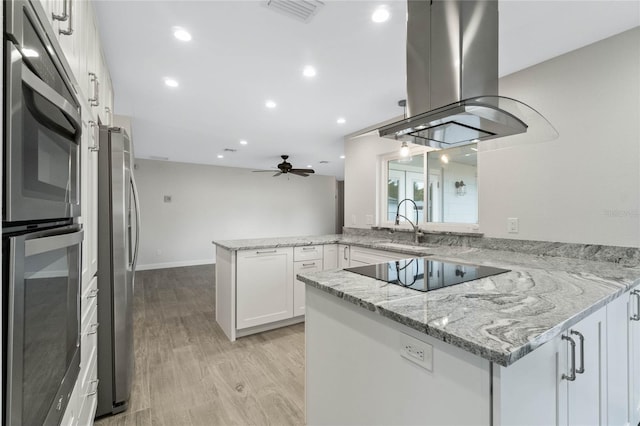 kitchen featuring ceiling fan, kitchen peninsula, appliances with stainless steel finishes, white cabinets, and island range hood