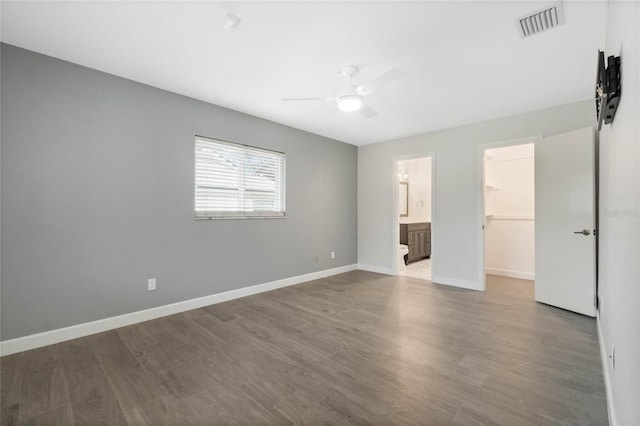 interior space with a spacious closet, hardwood / wood-style floors, ceiling fan, connected bathroom, and a closet