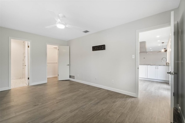 unfurnished bedroom with ceiling fan, hardwood / wood-style flooring, a closet, and a walk in closet