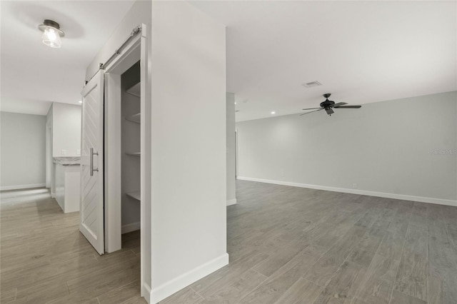 hall with a barn door and light wood-type flooring