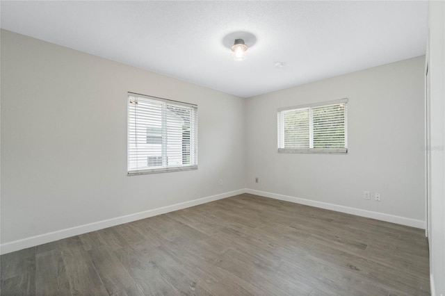 empty room featuring plenty of natural light and dark hardwood / wood-style flooring