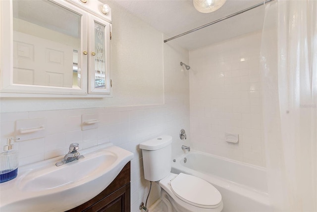 full bathroom featuring a textured ceiling, vanity, shower / tub combo, tile walls, and toilet