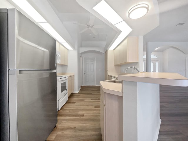 kitchen featuring ceiling fan, sink, white appliances, light wood-type flooring, and a kitchen breakfast bar