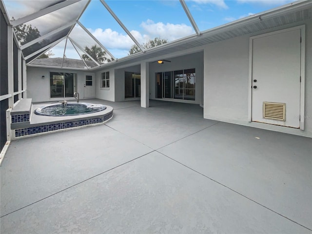 exterior space with glass enclosure, a hot tub, and a patio