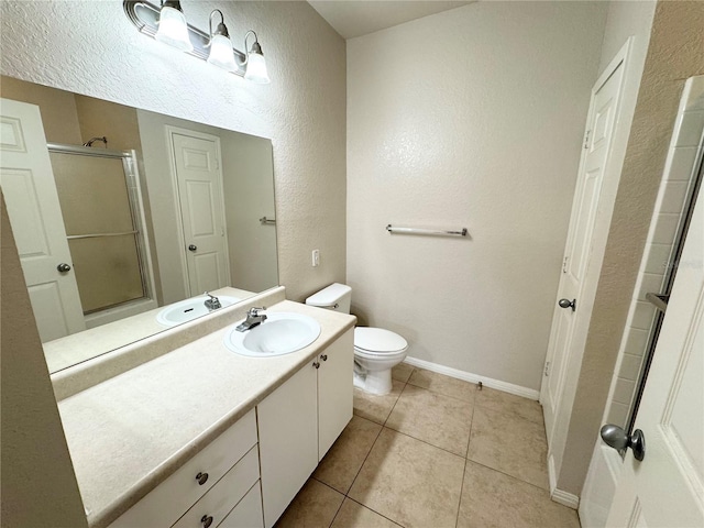 bathroom featuring baseboards, toilet, a shower with door, tile patterned flooring, and vanity