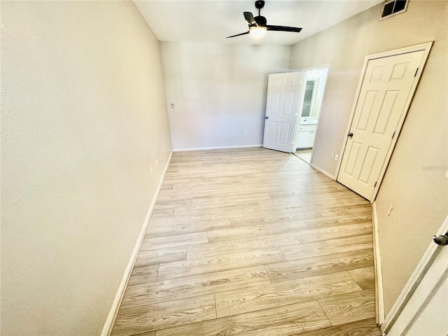 empty room featuring visible vents, ceiling fan, light wood-style flooring, and baseboards