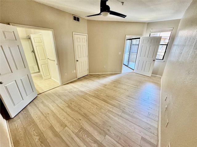 unfurnished bedroom featuring light wood finished floors, visible vents, ceiling fan, ensuite bath, and baseboards