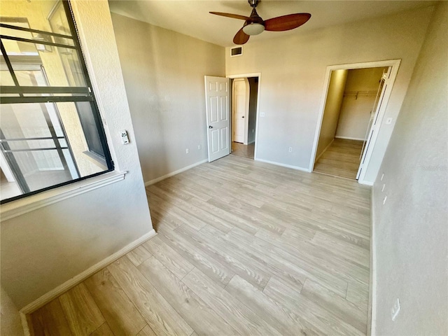 interior space featuring a ceiling fan, visible vents, baseboards, and wood finished floors