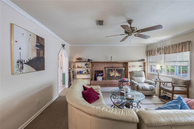 carpeted living room with a textured ceiling, ceiling fan, a brick fireplace, and crown molding