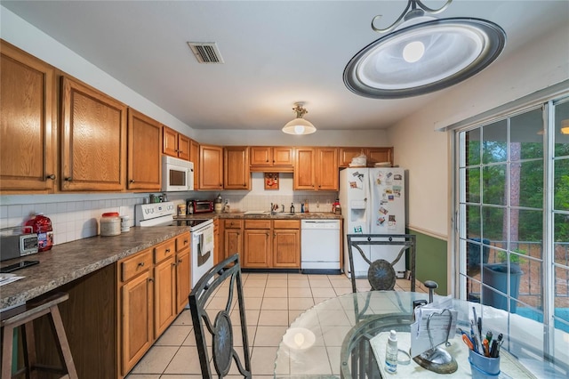 kitchen featuring sink, white appliances, tasteful backsplash, light tile patterned floors, and pendant lighting