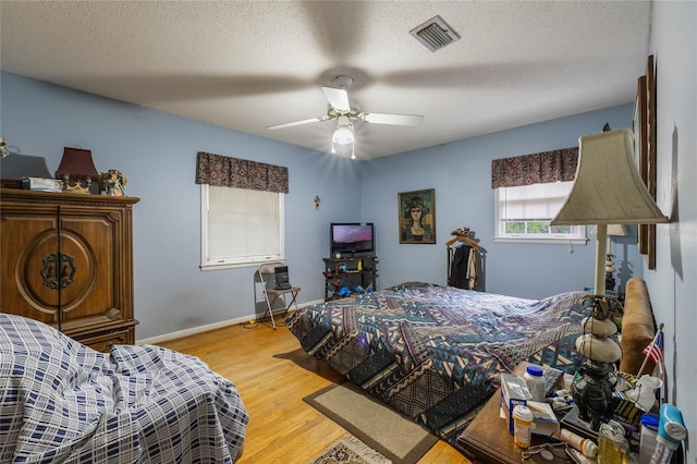 bedroom featuring a textured ceiling, ceiling fan, and light hardwood / wood-style flooring