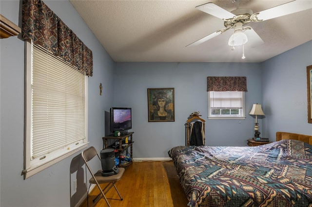 bedroom with ceiling fan, a textured ceiling, and hardwood / wood-style flooring