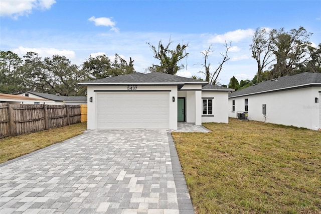 view of front of property featuring a front yard, a garage, and central AC