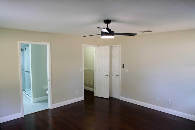 unfurnished bedroom with ceiling fan, connected bathroom, dark wood-type flooring, a closet, and a walk in closet