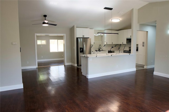 kitchen with decorative light fixtures, vaulted ceiling, sink, appliances with stainless steel finishes, and white cabinets