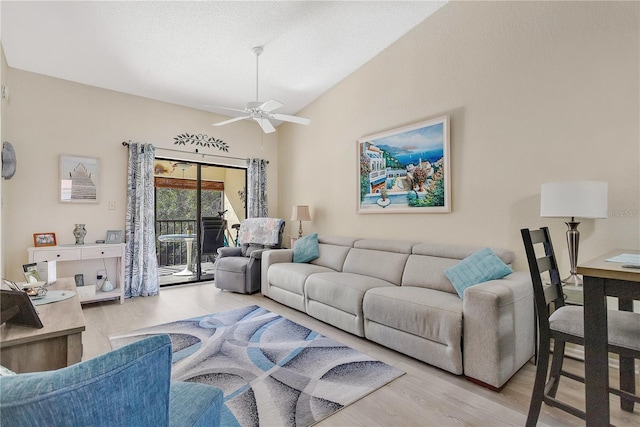 living room featuring ceiling fan, light wood-type flooring, and vaulted ceiling