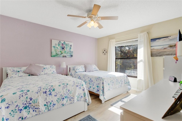 bedroom featuring ceiling fan, light hardwood / wood-style floors, and a textured ceiling