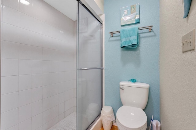 bathroom with toilet and a shower with door