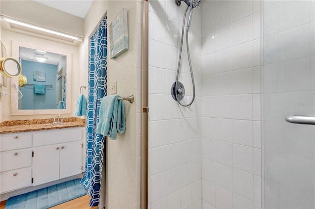 bathroom with a tile shower, wood-type flooring, and vanity