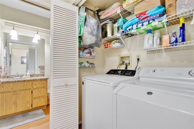 laundry area with sink, light hardwood / wood-style flooring, and washer and clothes dryer