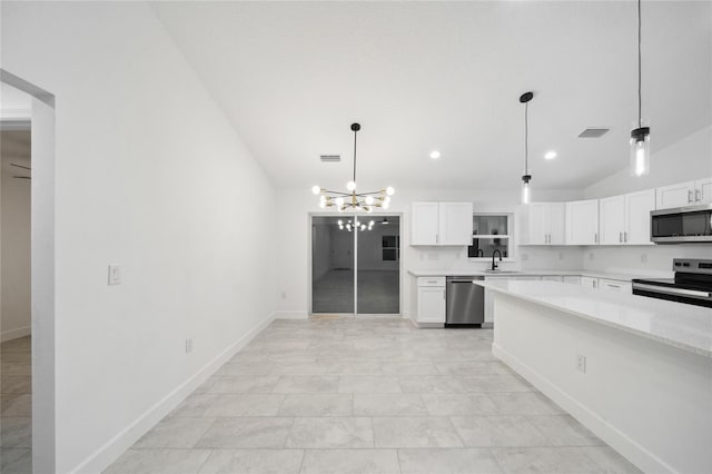 kitchen featuring lofted ceiling, decorative light fixtures, sink, appliances with stainless steel finishes, and white cabinets