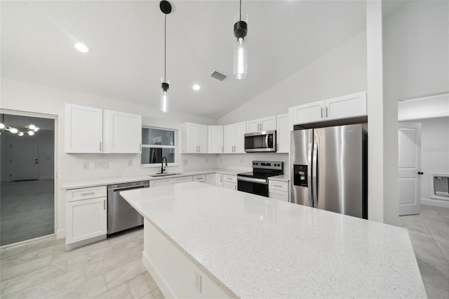 kitchen with light stone countertops, white cabinets, appliances with stainless steel finishes, sink, and hanging light fixtures