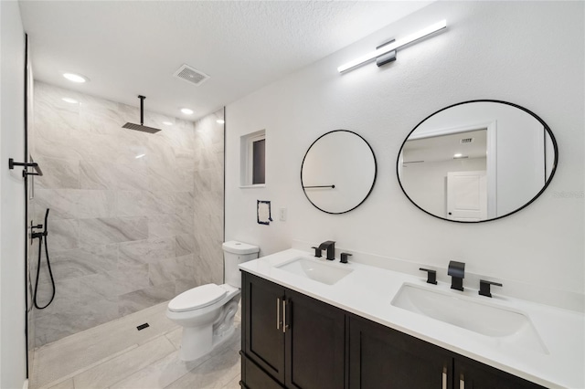 bathroom with a textured ceiling, tile patterned floors, vanity, toilet, and tiled shower