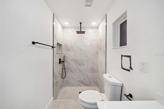 bathroom with toilet, tile patterned floors, and a tile shower