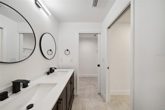 bathroom featuring a textured ceiling, tile patterned flooring, and vanity