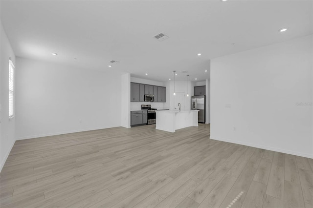 unfurnished living room with sink and light hardwood / wood-style floors