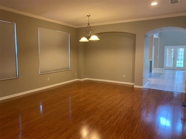 spare room with french doors, hardwood / wood-style flooring, a chandelier, and ornamental molding