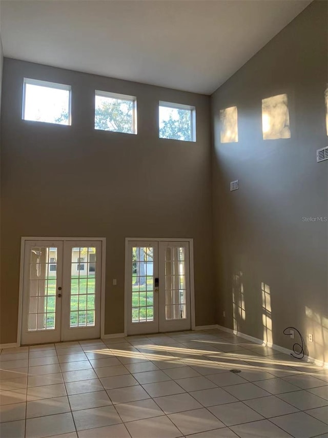 doorway with a wealth of natural light, tile patterned flooring, a towering ceiling, and french doors