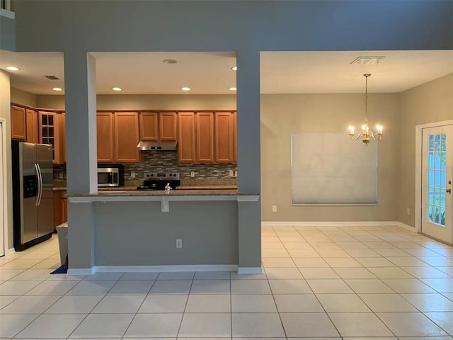 kitchen featuring light tile patterned floors, appliances with stainless steel finishes, a kitchen bar, and kitchen peninsula