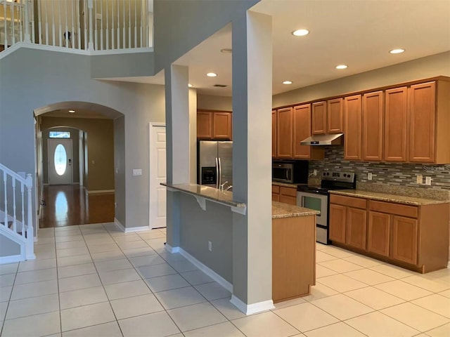 kitchen with light tile patterned floors, stainless steel appliances, decorative backsplash, and light stone countertops