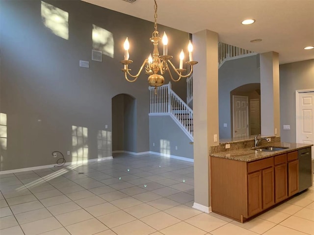 kitchen with stainless steel dishwasher, sink, a notable chandelier, light tile patterned floors, and stone counters