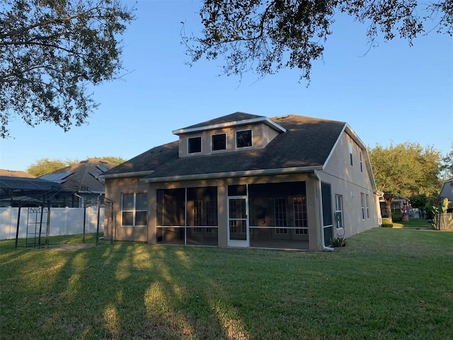 back of house featuring a sunroom and a lawn