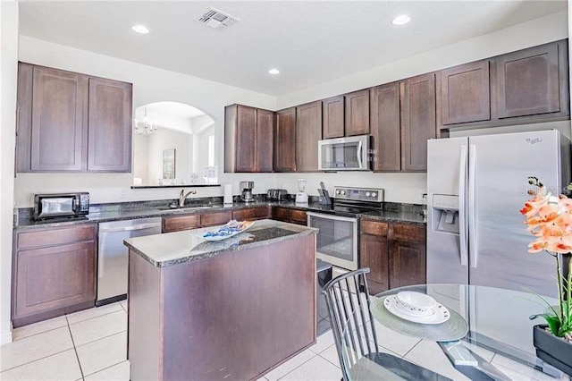 kitchen featuring sink, appliances with stainless steel finishes, light tile patterned floors, and a center island