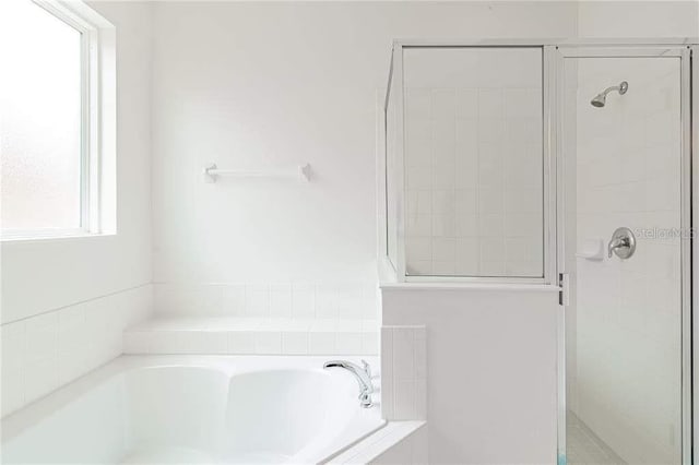 bathroom with shower with separate bathtub and a healthy amount of sunlight