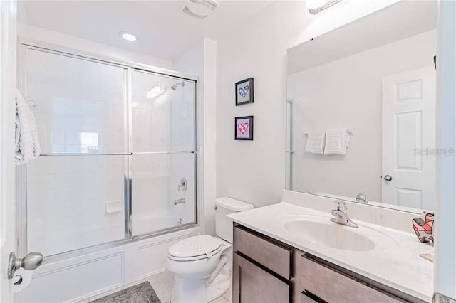 full bathroom featuring tile patterned floors, shower / bath combination with glass door, vanity, and toilet