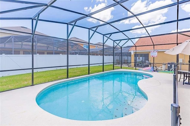 view of pool with a yard, glass enclosure, and a patio