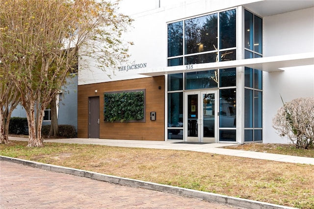 view of exterior entry featuring french doors and a yard