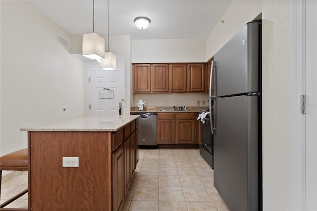 kitchen featuring light stone counters, hanging light fixtures, stainless steel appliances, a breakfast bar, and light tile patterned flooring