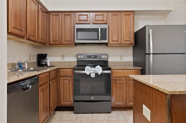 kitchen featuring sink, stainless steel appliances, light stone countertops, and light tile patterned floors