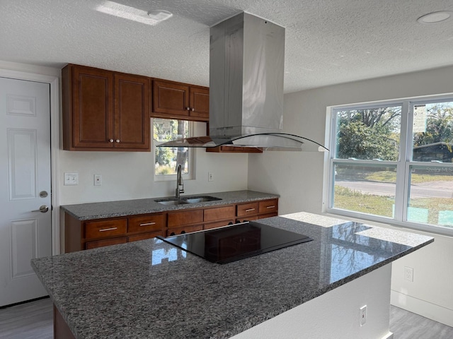 kitchen featuring sink, a textured ceiling, light hardwood / wood-style floors, island range hood, and black electric stovetop