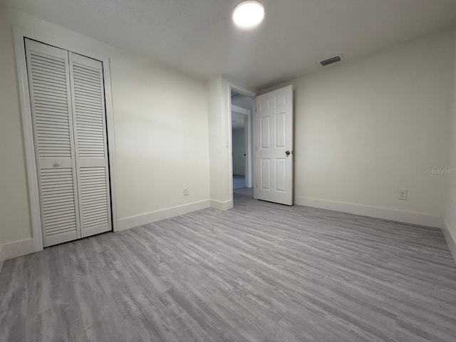 unfurnished bedroom with a closet and light hardwood / wood-style floors